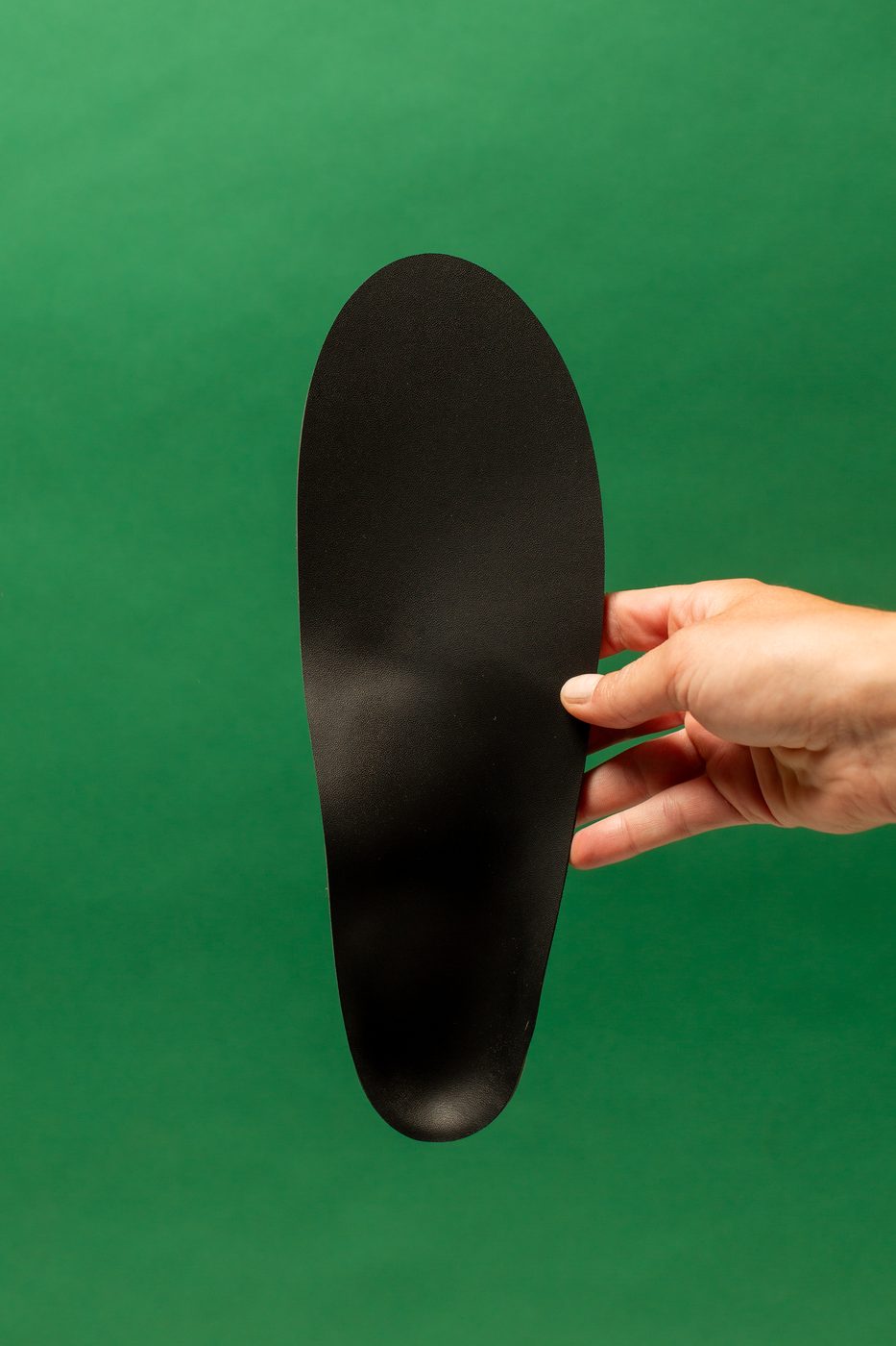 A hand holding a finished black HDPE orthotic shell.