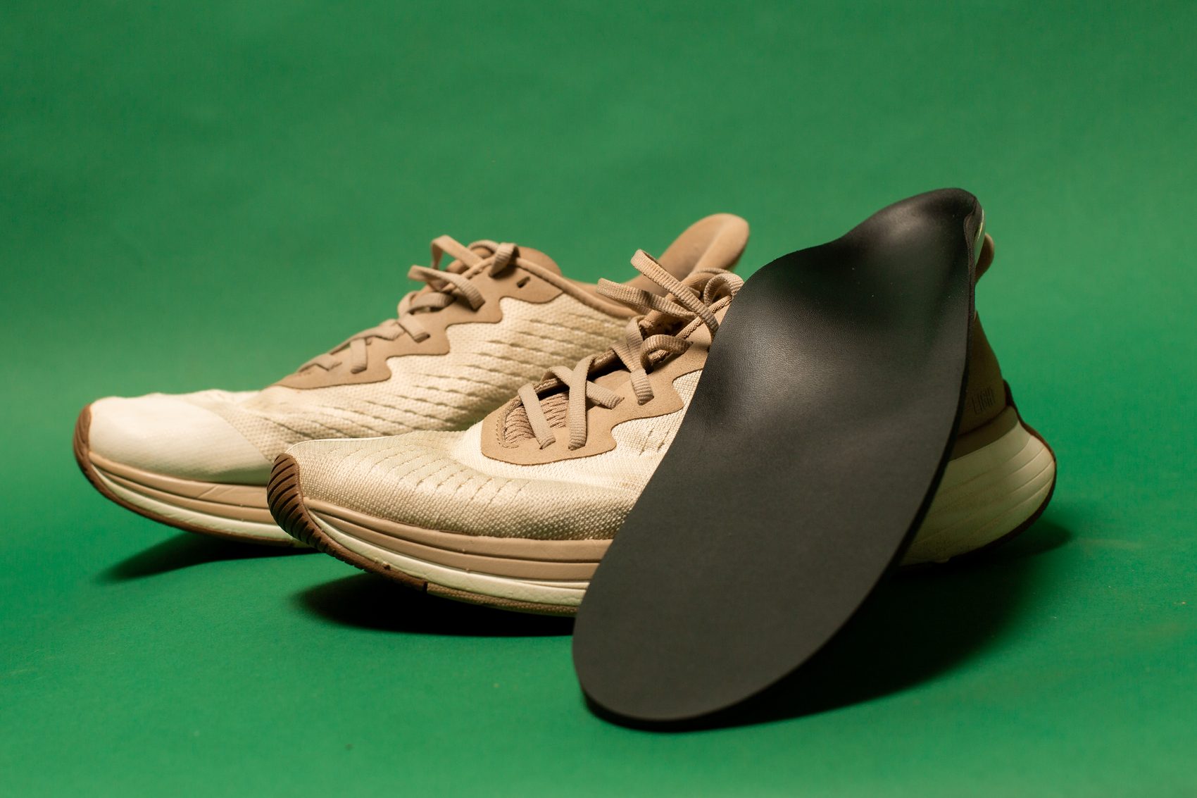 A pair of running shoes beside a ReLEAF ready-to-wear orthotic.